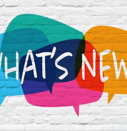 A white brick wall with four colorful speech bubbles and the words “WHAT’S NEW?” in white.
