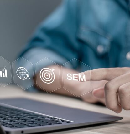 A person’s torso in front of a laptop with digital marketing icons in the air and they are touching the one that says “SEM.”