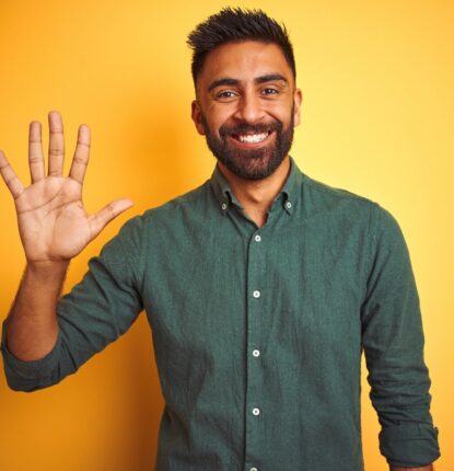 A smiling man wearing a green button-down shirt while holding up the five fingers of one hand.