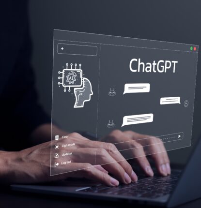 Conceptual image of a person’s hands over a laptop keyboard with a graphic depicting a ChatGPT window with chat bubbles in it hovering over the hands.