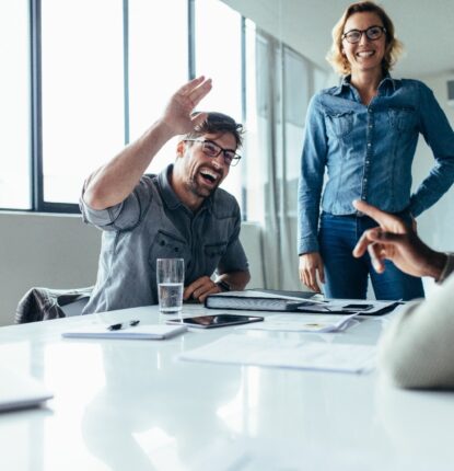 A team of coworkers in a conference room talking and laughing while they develop their brand voice.