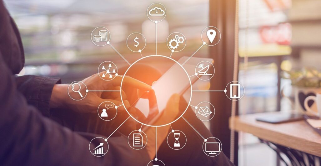 A business person holding a tablet with a white circle over it that is the center of several other circles that represent multichannel marketing.