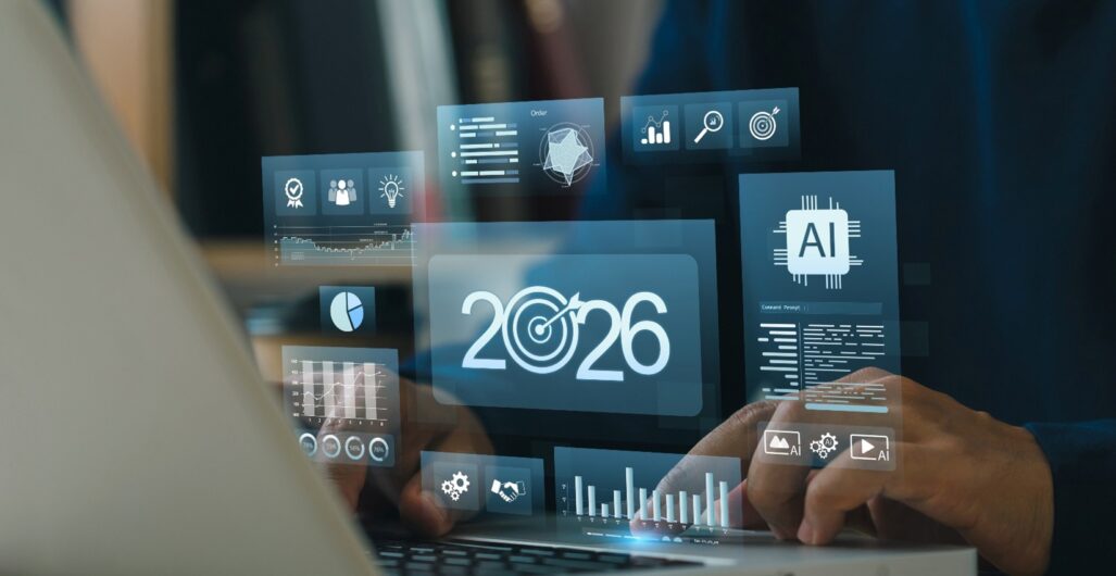 Hands on laptop with holographic dashboards showing 2026, target icon, AI chip, charts, and KPIs, illustrating business goals, growth strategy, data analytics, forecasting, and digital transformation.